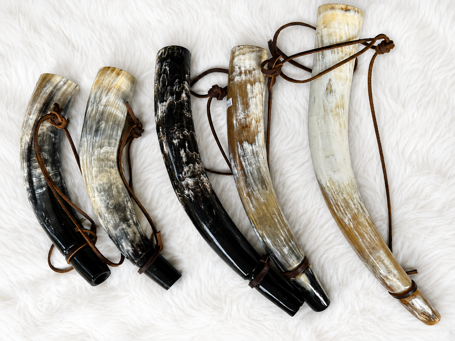 Sounding Horns of different sizes laying on a white fur background